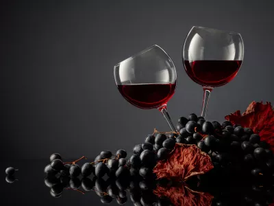 Glasses of red wine and blue grapes on a black background. Copy space. / Foto: Igorr1