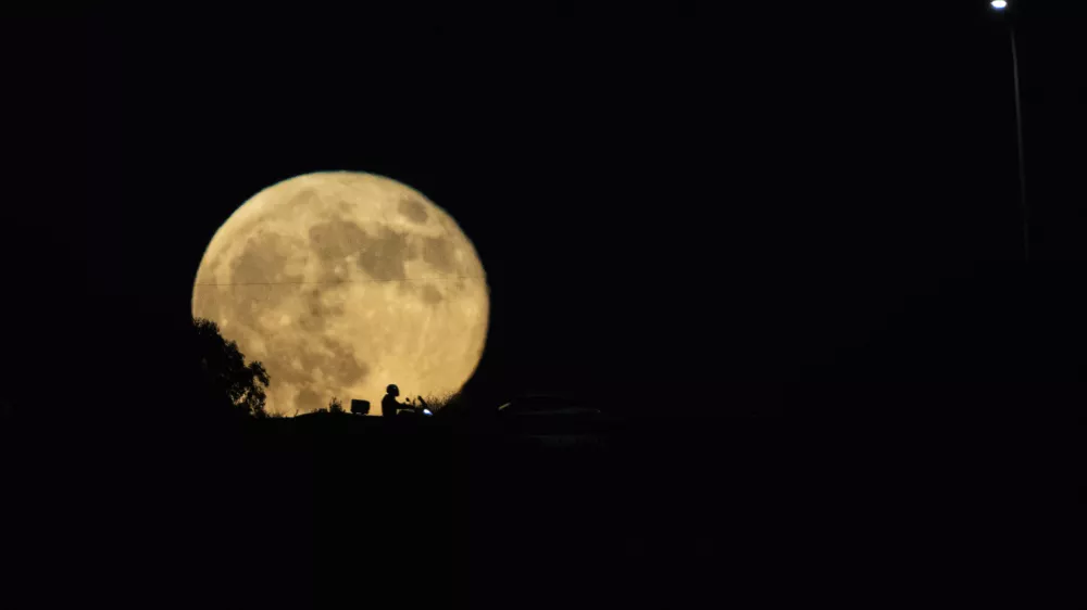 The moon rises in the sky over a freeway as drivers pass between Haifa and Tel Aviv, Israel, Wednesday, Sept. 18, 2024. (AP Photo/Ariel Schalit)