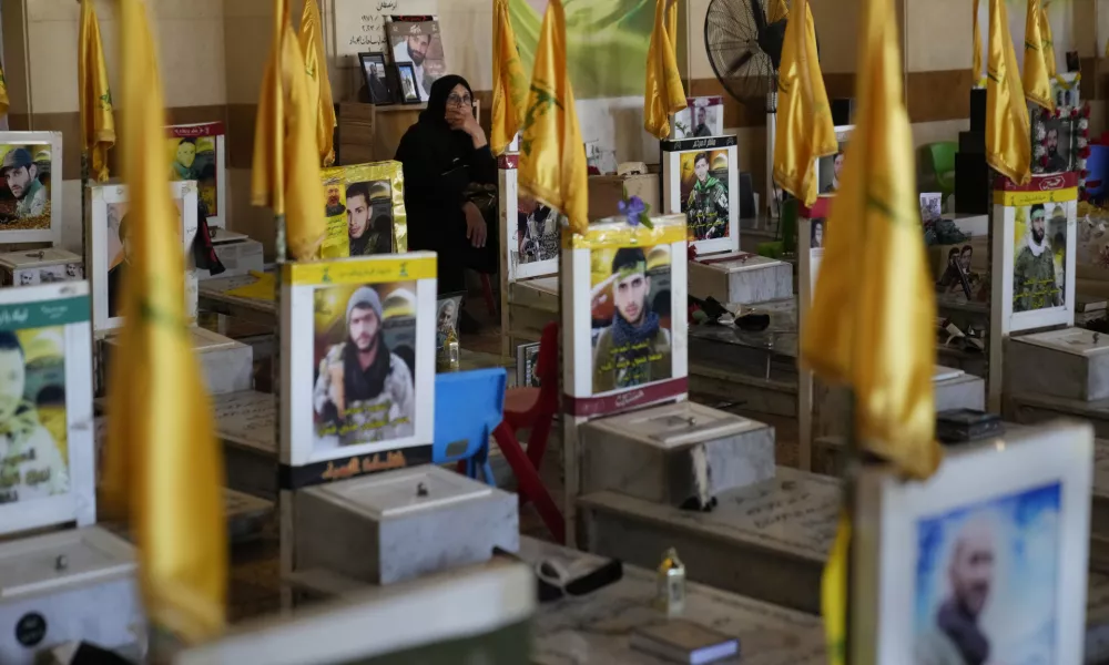 A woman sits in a cemetery as she visits the graves of killed Hezbollah members in the southern suburbs of Beirut, Thursday, Sept. 19, 2024. (AP Photo/Hussein Malla)