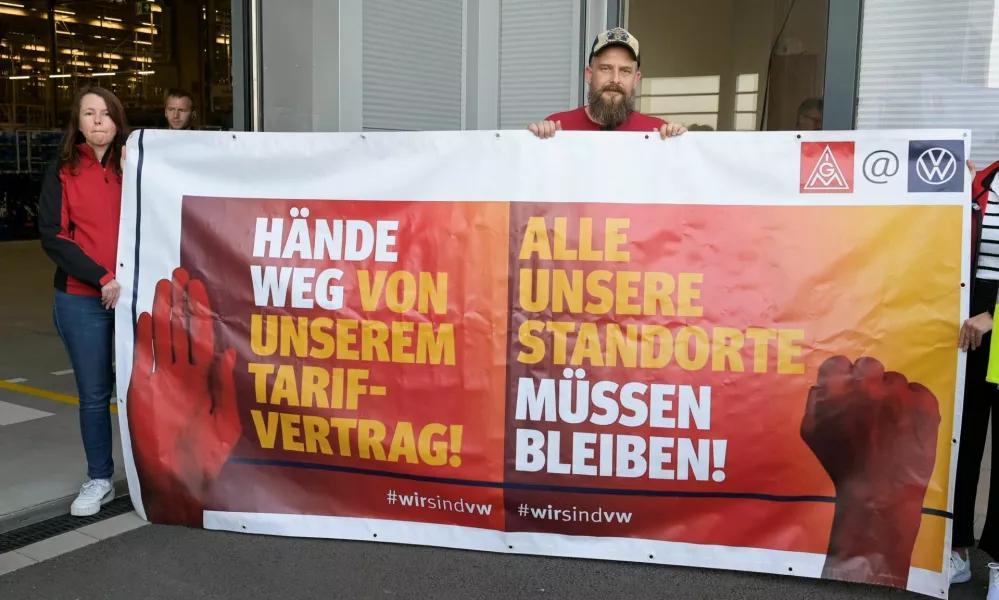 Protesters from German union IG Metall pose with a banner that reads, "Hands off our collective agreement", and "All our locations must remain", as German Economy Minister Robert Habeck visits a Volkswagen plant in Emden, Germany September 20, 2024. REUTERS/Fabian Bimmer