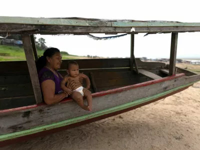 A woman sits on a boat with a baby, on the dry area of the Lake Tefe during the worst drought on the record, that has lowered the water level of the rivers and lakes in the Amazon basin to historic lows, in Tefe, Amazonas state, Brazil September 18, 2024. REUTERS/Jorge Silva