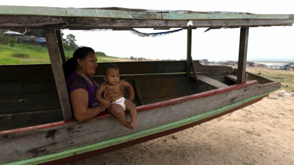 A woman sits on a boat with a baby, on the dry area of the Lake Tefe during the worst drought on the record, that has lowered the water level of the rivers and lakes in the Amazon basin to historic lows, in Tefe, Amazonas state, Brazil September 18, 2024. REUTERS/Jorge Silva