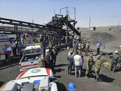 In this photo released by Iranian Red Crescent Society, rescue personnel, police officers and some other people gather around the site of a coal mine where methane leak sparked an explosion on Saturday, in Tabas, some 335 miles (540 kilometers) southeast of the capital Tehran, Iran, Sunday, Sept. 22, 2024. (Iranian Red Crescent Society, via AP)