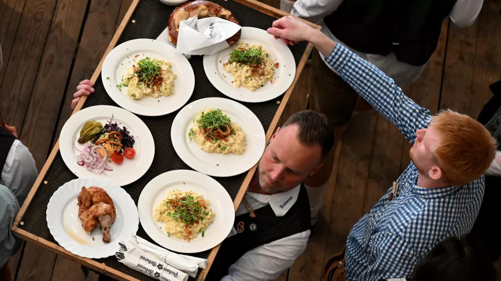 A waiter carries food on the day of the official opening of the 189th Oktoberfest, the world's largest beer festival in Munich, Germany, September 21, 2024. REUTERS/Angelika Warmuth