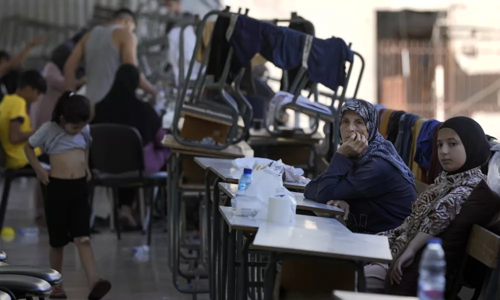 Displaced women and children sit in a classroom in Beirut, after fleeing the Israeli airstrikes in the south, Thursday, Sept. 26, 2024. (AP Photo/Bilal Hussein)