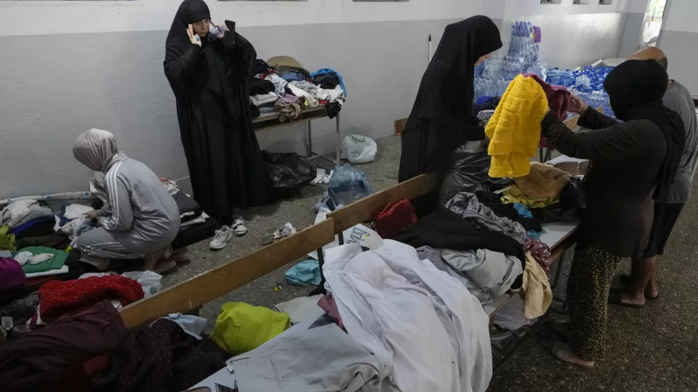 Volunteers distribute clothes to displayed women at a school in Beirut, Thursday, Sept. 26, 2024. (AP Photo/Bilal Hussein)