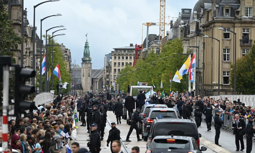 26 September 2024, Luxembourg: Spectators wait in the city center to see Pope Francis in the papamobile (Back) during his visit to Luxembourg. Photo: Harald Tittel/dpa