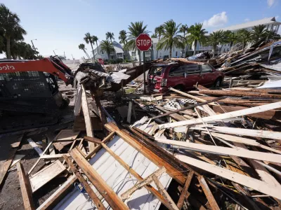 Workers clear debris in the aftermath of Hurricane Helene, in Cedar Key, Fla., Friday, Sept. 27, 2024. (AP Photo/Gerald Herbert)