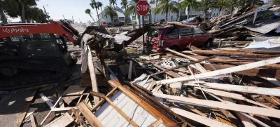 Workers clear debris in the aftermath of Hurricane Helene, in Cedar Key, Fla., Friday, Sept. 27, 2024. (AP Photo/Gerald Herbert)