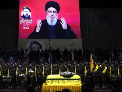 FILE - Hezbollah fighters stand behind the coffin of their top commander Fouad Shukur, who was killed by an Israeli airstrike on July 30, as Hezbollah leader Sayyed Hassan Nasrallah speaks through a screen during Shukur's funeral in a southern suburb of Beirut, Lebanon, Aug. 1, 2024. (AP Photo/Hussein Malla, File)