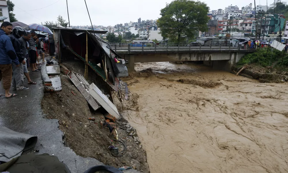 People gather at the edge of the Bagmati River in spate after heavy rains in Kathmandu, Nepal, Saturday, Sept. 28, 2024. (AP Photo/Gopen Rai)