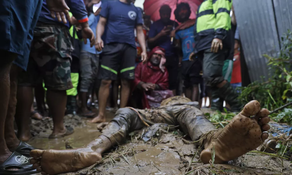 EDS NOTE: GRAPHIC CONTENT - People, including relatives, stand by the body of Nandu Sah, 34, a scrap dealer, who died after the shed he was sleeping under was flooded due to heavy rains, on the outskirts of Kathmandu, Nepal, Saturday, Sept. 28, 2024. (AP Photo/Gopen Rai)