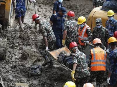 EDS NOTE: GRAPHIC CONTENT - Rescue personnel transport the dead body of a victim who was trapped under a landslide caused by heavy rains in Kathmandu, Nepal, Sunday, Sept. 29, 2024. (AP Photo/Sujan Gurung)