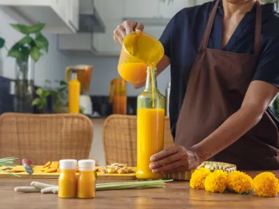 Close up of woman preparing homemade Jamu drink- Indonesian herbal beverage with natural ingredients: turmeric, ginger, lime, lemongrass, tamarind, lemongrass in kitchen. Healthy lifestyle concept / Foto: Space_cat