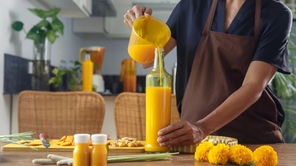 Close up of woman preparing homemade Jamu drink- Indonesian herbal beverage with natural ingredients: turmeric, ginger, lime, lemongrass, tamarind, lemongrass in kitchen. Healthy lifestyle concept / Foto: Space_cat