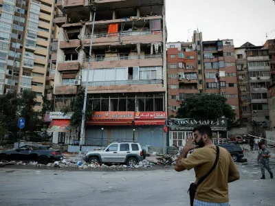 People pass by buildings damaged in an Israeli strike, amid ongoing cross-border hostilities between Hezbollah and Israeli forces, in Kola, central Beirut, Lebanon September 30, 2024. REUTERS/Louisa Gouliamaki