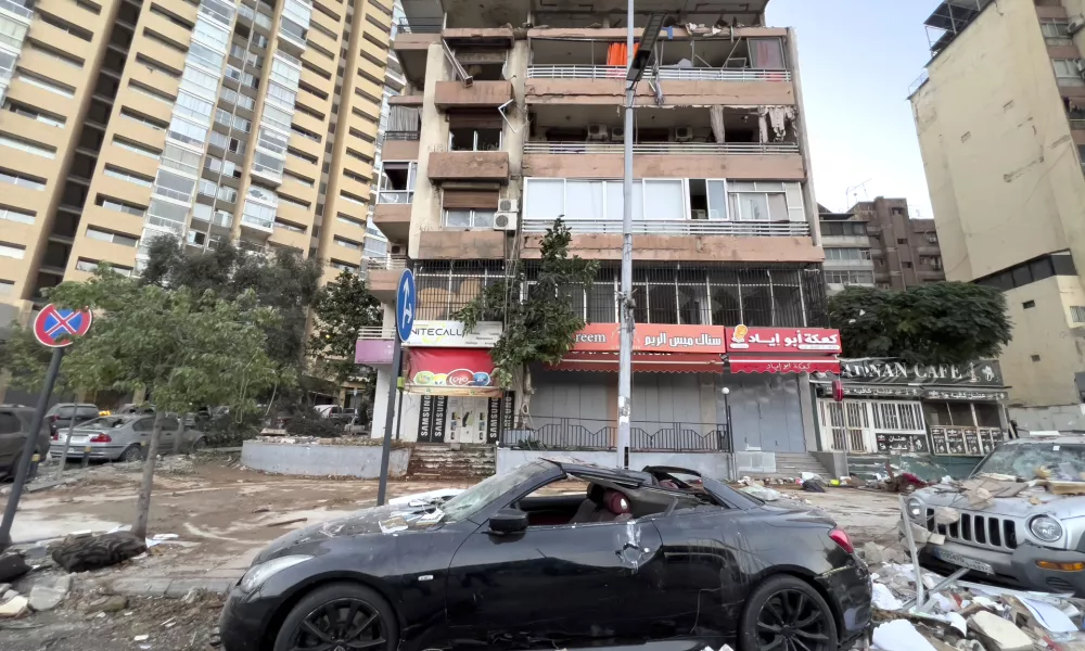 Damaged cars are parked in front of a building that was hit by an Israeli airstrike early Monday, Sept. 30, 2024. (AP Photo/Hussein Malla)