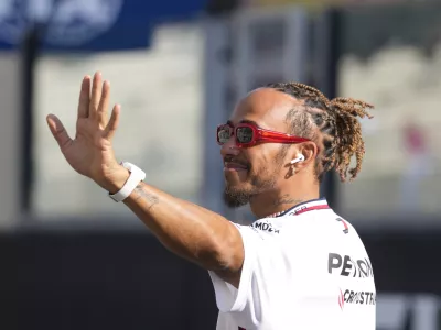 FILE - Mercedes driver Lewis Hamilton of Britain, waves as he arrives for the F1 drivers group picture ahead the drivers parade prior to the Abu Dhabi Formula One Grand Prix at the Yas Marina racetrack in Abu Dhabi, United Arab Emirates, Sunday, Nov. 26, 2023. Seven-time Formula One champion Lewis Hamilton has been linked with a shock move from Mercedes to Ferrari next year. (AP Photo/Kamran Jebreili, File)