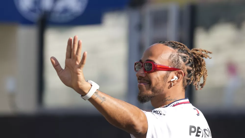 FILE - Mercedes driver Lewis Hamilton of Britain, waves as he arrives for the F1 drivers group picture ahead the drivers parade prior to the Abu Dhabi Formula One Grand Prix at the Yas Marina racetrack in Abu Dhabi, United Arab Emirates, Sunday, Nov. 26, 2023. Seven-time Formula One champion Lewis Hamilton has been linked with a shock move from Mercedes to Ferrari next year. (AP Photo/Kamran Jebreili, File)