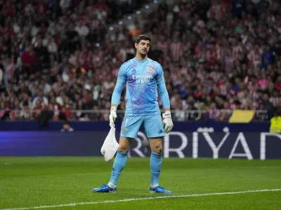 Real Madrid's goalkeeper Thibaut Courtois holds a bag, thrown by Atletico Madrid fans, during the La Liga soccer match between Atletico Madrid and Real Madrid at the Metropolitano stadium in Madrid, Spain, Sunday, Sept. 29, 2024. (AP Photo/Bernat Armangue)