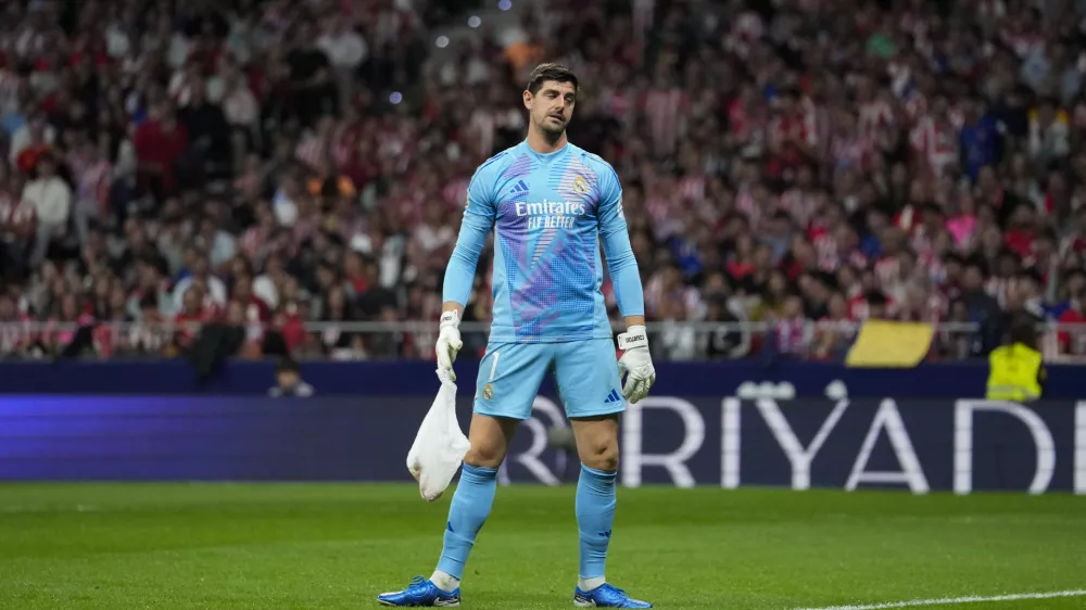 Real Madrid's goalkeeper Thibaut Courtois holds a bag, thrown by Atletico Madrid fans, during the La Liga soccer match between Atletico Madrid and Real Madrid at the Metropolitano stadium in Madrid, Spain, Sunday, Sept. 29, 2024. (AP Photo/Bernat Armangue)