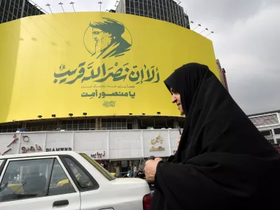 An Iranian woman walks past a huge banner of slain Hezbollah leader Hassan Nasrallah installed on a building at a square in downtown Tehran, Iran, Sunday, Sept. 29, 2024. The banner reads a verse of the Quran: "God's help is definitely close." (AP Photo/Vahid Salemi)