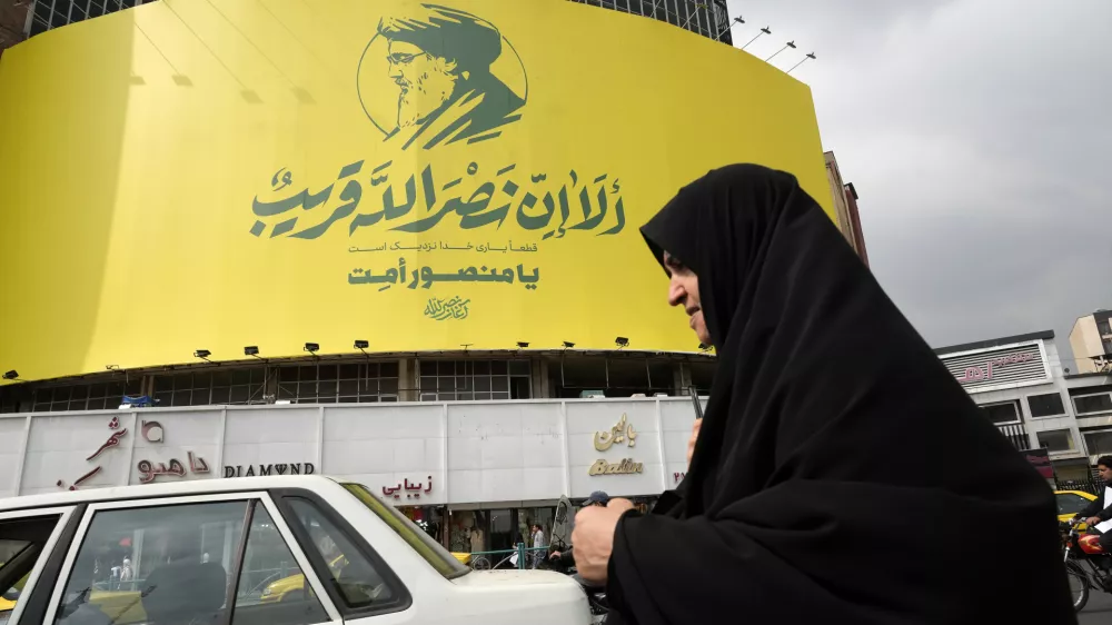 An Iranian woman walks past a huge banner of slain Hezbollah leader Hassan Nasrallah installed on a building at a square in downtown Tehran, Iran, Sunday, Sept. 29, 2024. The banner reads a verse of the Quran: "God's help is definitely close." (AP Photo/Vahid Salemi)