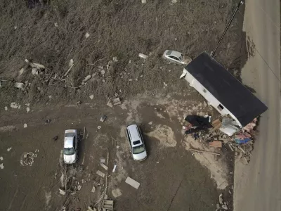 A destroyed mobile home and vehicles lay scattered across muddy land, Tuesday, Oct. 1, 2024, in Hendersonville, N.C., in the aftermath of Hurricane Helene. (AP Photo/Brittany Peterson)