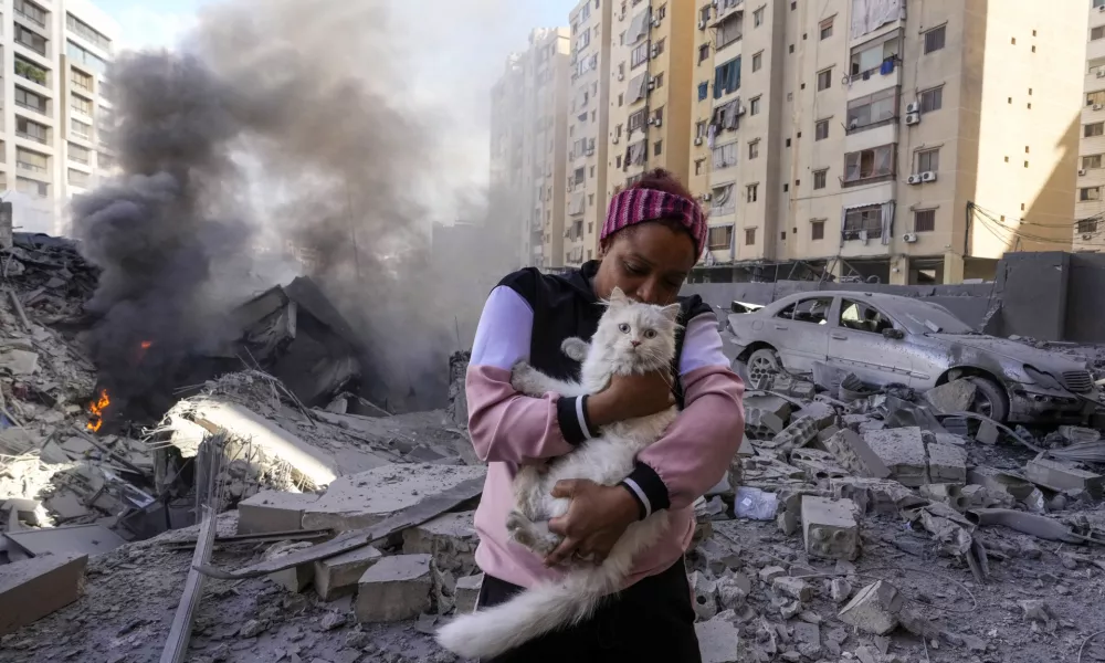 A woman holds her cat in front of a destroyed building at the site of an Israeli airstrike in Dahiyeh, Beirut, Lebanon, Wednesday, Oct. 2, 2024. (AP Photo/Hassan Ammar)