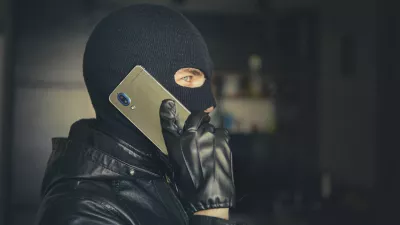 Young adult in black clothes with hidden face. Ill-intended fraudster uses mobile. Fraudster calls. Mobile racket. Hacker hijacks by phone. Cellphone account fraud. Scam / Foto: Diy13