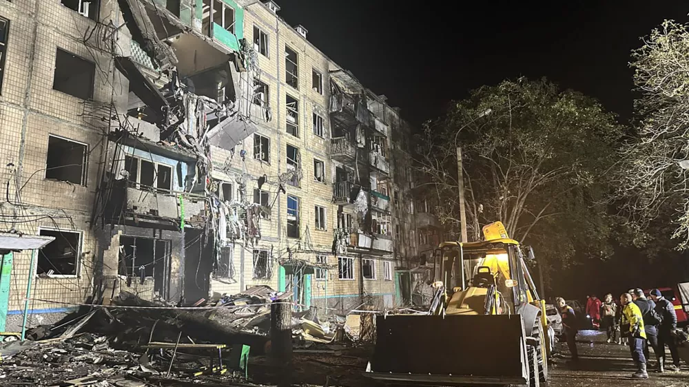 People gather around the damage and debris after a Russian strike on a residential building in Kharkiv, Ukraine, late Wednesday Oct. 2, 2024. (Ukrainian National Police via AP)