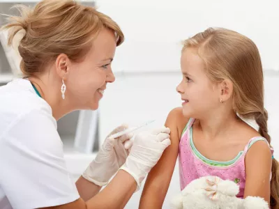 ﻿Brave little girl receiving injection or vaccine with a smile