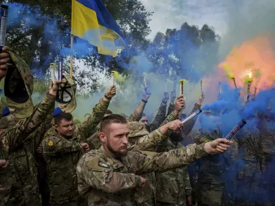 Ukrainian servicemen of the Azov brigade light flares during the funeral ceremony of fallen comrade Ihor Kusochek, in Travkine, Chernihiv region, Ukraine, Friday Oct. 4, 2024. (AP Photo/Evgeniy Maloletka)