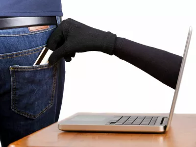 Internet theft - Concept: a gloved hand reaching through a laptop screen to steal a wallet from a man's pocket. / Foto: Davidevison