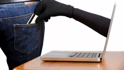 Internet theft - Concept: a gloved hand reaching through a laptop screen to steal a wallet from a man's pocket. / Foto: Davidevison