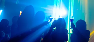 Silhouette image of people dance in disco night club to music from DJ on stage. New year night party and nightlife concept. / Foto: Nanostockk