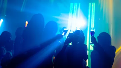 Silhouette image of people dance in disco night club to music from DJ on stage. New year night party and nightlife concept. / Foto: Nanostockk