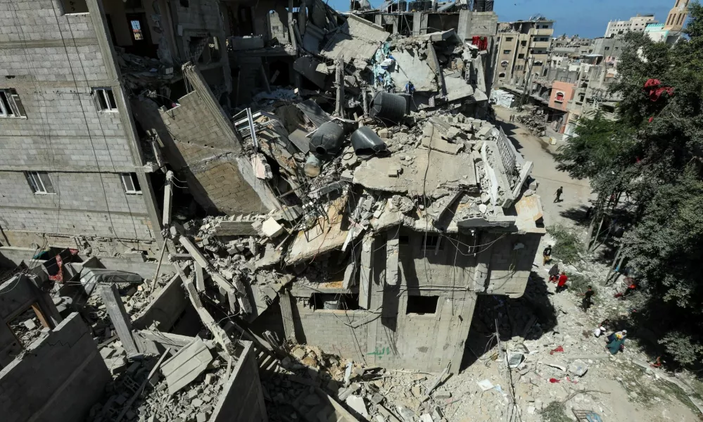 Palestinians walk past a house hit in an Israeli strike, amid the Israel-Hamas conflict, in Bureij refugee camp, in the central Gaza Strip, October 8, 2024. REUTERS/Ramadan Abed