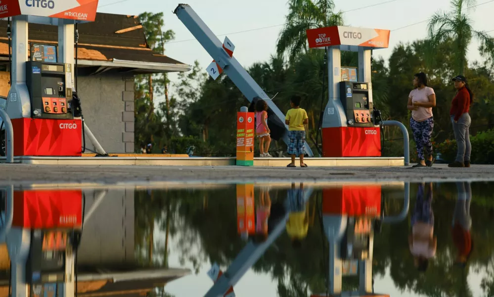 People stand near a bent structure at a gas station, after Hurricane Milton made landfall, in Lakewood Park, near Fort Pierce, in St. Lucie County, Florida, U.S., October 10, 2024. REUTERS/Jose Luis Gonzalez