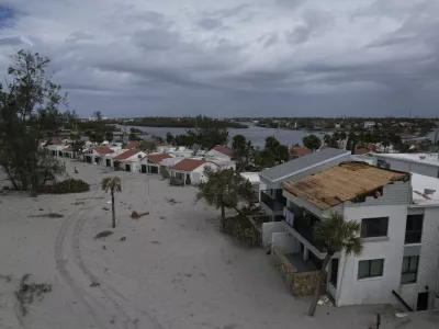 The damaged roof of Ron and Jean Dyer's beachfront condo at Bahia Vista Gulf is seen alongside the sand-swamped Jetty Villas, after the passage of Hurricane Milton, on the island of Venice, Fla., Friday, Oct. 11, 2024. (AP Photo/Rebecca Blackwell)