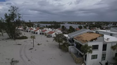 The damaged roof of Ron and Jean Dyer's beachfront condo at Bahia Vista Gulf is seen alongside the sand-swamped Jetty Villas, after the passage of Hurricane Milton, on the island of Venice, Fla., Friday, Oct. 11, 2024. (AP Photo/Rebecca Blackwell)