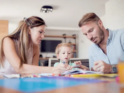 Smiling family drawing together in living room at home.