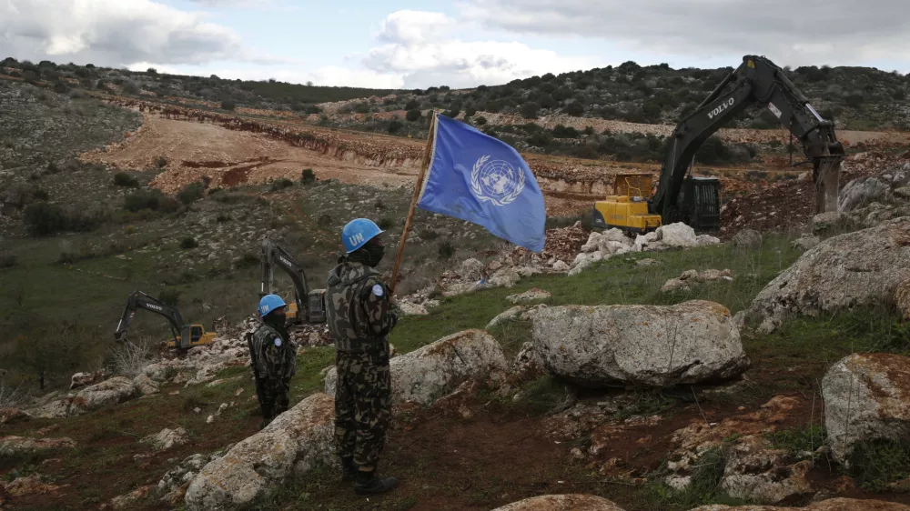 FILE - UN peacekeepers hold their flag, as they observe Israeli excavators attempt to destroy tunnels built by Hezbollah, near the southern Lebanese-Israeli border village of Mays al-Jabal, Lebanon, Dec. 13, 2019. (AP Photo/Hussein Malla, File)