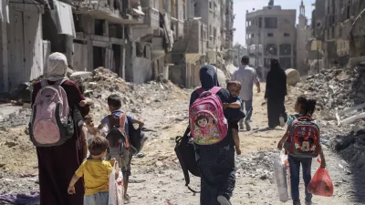 FILE - Palestinian women and their children walk though destruction in the wake of an Israeli air and ground offensive in Jebaliya, northern Gaza Strip after Israeli forces withdrew from the area, on May 31, 2024. (AP Photo/Enas Rami)