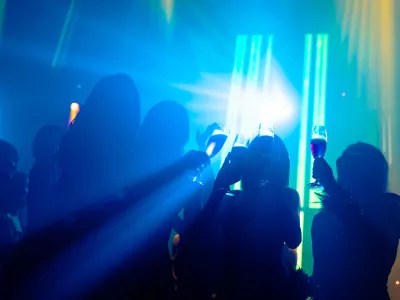 Silhouette image of people dance in disco night club to music from DJ on stage. New year night party and nightlife concept.