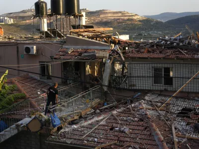 A member of Israeli security forces surveys damage to a home struck by a rocket fired from Lebanon in the town of Majd al-Krum, northern Israel, Wednesday, Oct. 16, 2024. (AP Photo/Ariel Schalit)