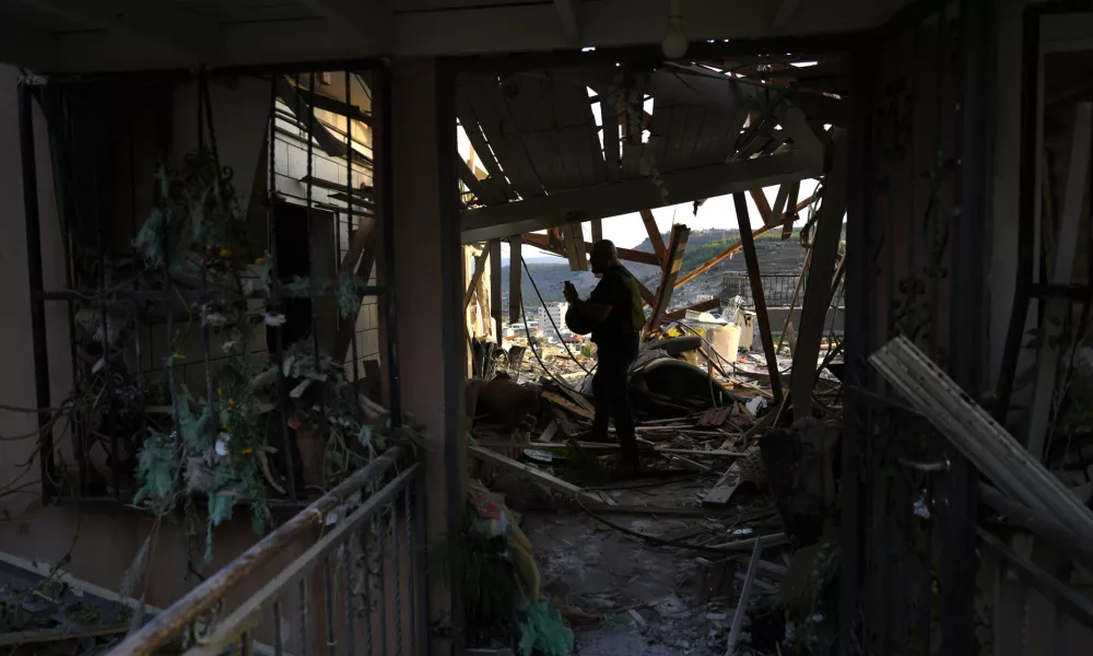 A member of Israeli security forces surveys damage to a home struck by a rocket fired from Lebanon in the town of Majd al-Krum, northern Israel, Wednesday, Oct. 16, 2024. (AP Photo/Ariel Schalit)