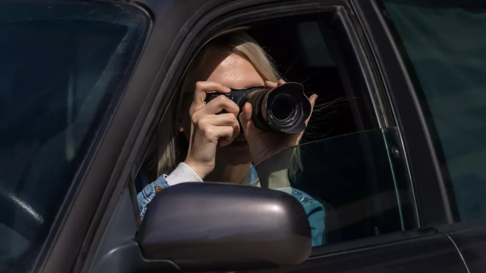 Hidden photographing. Paparazzi Concep Photographer uses his professional camera. Photographer girl in car window. Mobile reporter. Photojournalist at work. Detective or investigator. / Foto: Yaraslau Mikheyeu