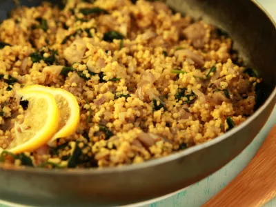 Vegetarian couscous with mushrooms and spinach. Vegan dish with millet in the frying pan. Close up. / Foto: Lora-sutyagina