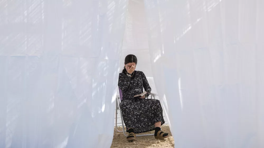 A Jewish woman prays in a sukkah, a small temporary hut constructed for the Jewish holiday of Sukkot, as part of a demonstration calling for Jewish resettlement of the Gaza Strip, near the Israeli-Gaza border, southern Israel, Monday, Oct. 21, 2024. (AP Photo/Tsafrir Abayov)